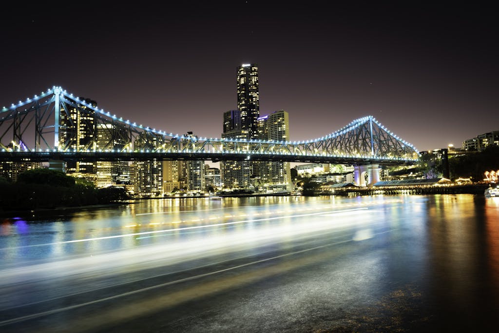 Bright cityscape view of Story Bridge in Brisbane at night with vibrant reflections on the river.